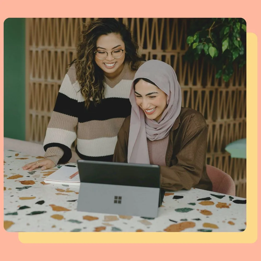 Two professionals collaborating on a laptop in a creative workspace